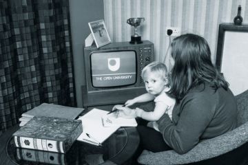 Woman watching The Open University on TV while holding child