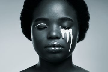 Black woman with white paint on her face to illustrate issue of diversity Black woman with white paint on her face to illustrate issue of diversity