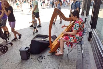 Woman busker playing the harp on O'Connell Street, Dublin city centre