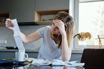 Woman calculating payment bill in kitchen