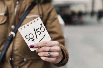 Woman holding up 50 50 gender sign