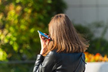 Woman listens to a voice message with her phone pressed to her ear Woman listens to a voice message with her phone pressed to her ear