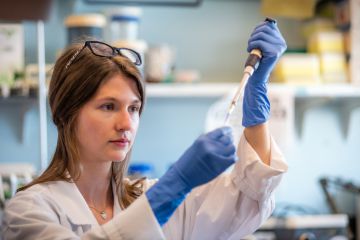 Woman researcher in biotechnology laboratory pipetting genetic material