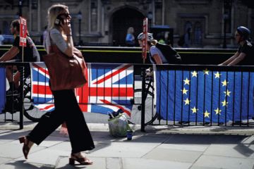 Woman walking past UK and EU flags Woman walking past UK and EU flags
