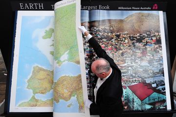 A man turns pages of what he calls "the world's largest book". To illustrate that the price of journal access agreements are becoming too big for universities after several publishers keep raising prices.