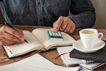 Man writing in a diary with calculator