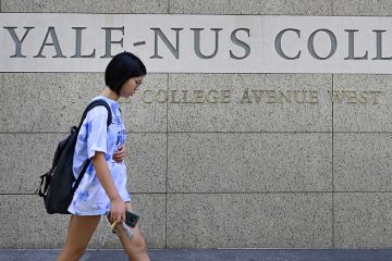A student walking past signage for the Yale-NUS College in Singapore