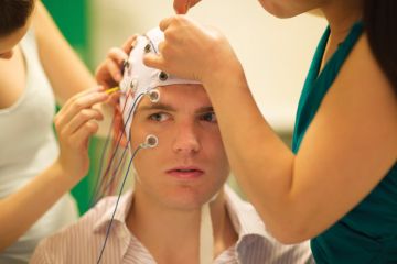 Young man being prepared for brain experiment Young man being prepared for brain experiment