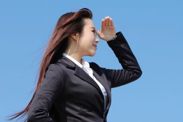 Young woman shielding eyes and looking into distance Young woman shielding eyes and looking into distance
