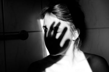 Young woman with shadow of hand over face