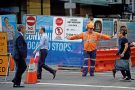A worker directs pedestrians on a street in the central business district of Sydney