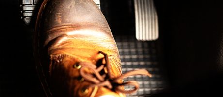 A foot pushes a car's brake pedal