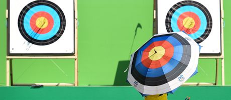  An archer holding an umbrella with a target design checks the target during the first day of an archery test event. To illustrate challenging new UKRI targets for industry-funded research.