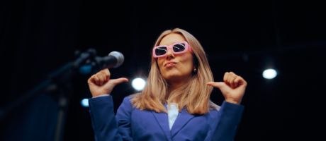A woman in pink glases points to herself, illustrating showing off on socail media A woman in pink glases points to herself, illustrating showing off on socail media