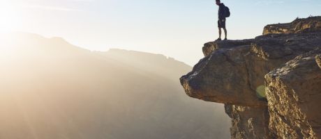 A man looks over the edge of a cliff, illustrating the drop-off in ERC funder in mid-career