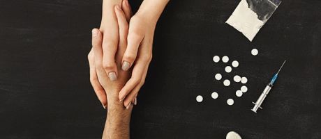 Hands held on a table of drugs, illustrating drug recovery support