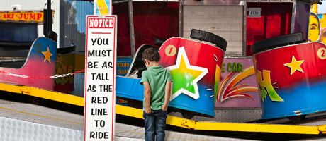 Fairground waltzers ride with minimum height safety notice and disappointed child. To illustrate minimum entry standards. Fairground waltzers ride with minimum height safety notice and disappointed child. To illustrate minimum entry standards.