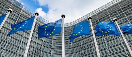 European flags waving in the wind side by side in front of the Berlaymont building facade, headquarters of the European Commission.