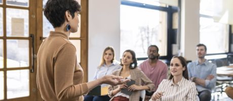 A woman giving a university lecture to several students 