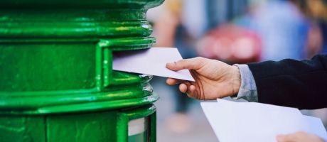  man posting mail into a postbox in the city