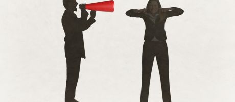 A man with a megaphone yells at a woman with her fingers in her ears A man with a megaphone yells at a woman with her fingers in her ears
