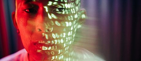 Numbers projected onto the face of an Asian man, symbolising metrics obsession