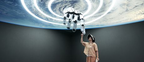 A woman touching a giant robot hand that looks like it is coming from the centre of a storm. To illustrate whether universities embracing AI is undermining their net-zero targets.
