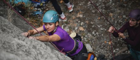 One rock climber hold the rope for another, illustrating a supportive research environment