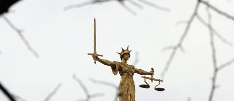 A statue of the scales of justice stands above the Old Bailey, London. To illustrate 
