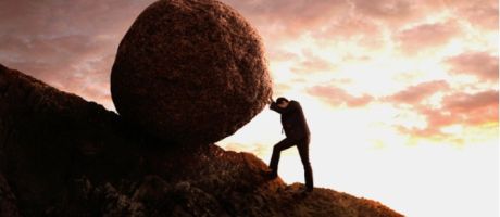 A businessman rolls a rock up a hill like Sisyphus