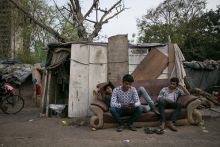 India young men sit on a sofa in a slum, illustrating graduate unemployment India young men sit on a sofa in a slum, illustrating graduate unemployment