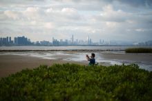 A man takes a photo from the shoreline of Hong Kong’s Deep Bay with the skyline of Chinese mainland city of Shenzhen visible behind him A man takes a photo from the shoreline of Hong Kong’s Deep Bay with the skyline of Chinese mainland city of Shenzhen visible behind him