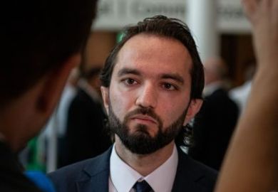 Iranian student Armin, who has dark hair and is wearing a suit and tie, looking to his right