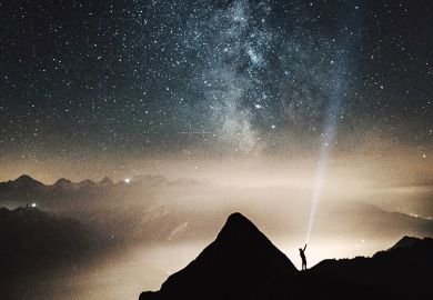 A man shining a torch up to the stars