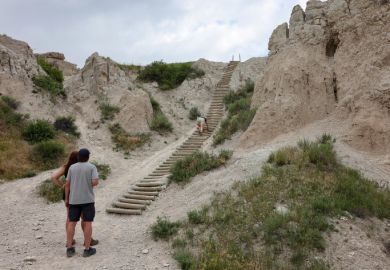 A hiker climbing the ladder of the Notch Trail at Badlands National Park, South Dakota