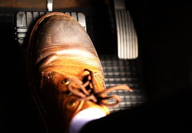 A foot pushes a car's brake pedal