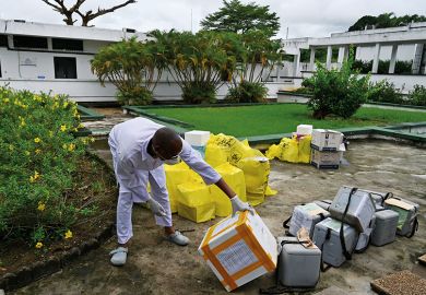 African worker in PPE inspects supplies