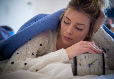 A young woman turns off an alarm clock