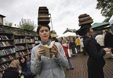 People balancing books on their heads at the Hay Literary Festival. To illustrate librarians needing to discard underused books due to lack of shelf space.