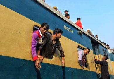 People lean out of a train window in Bangladesh, illustrating academic freedom