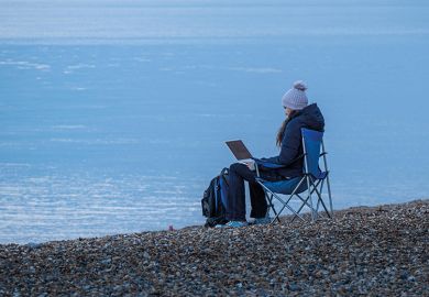 Working on laptop by sea in winter