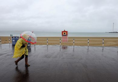 Person walking in the rain on beach in Weymouth Person walking in the rain on beach in Weymouth