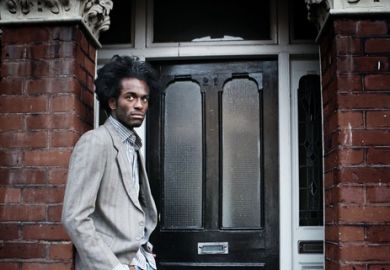 A black man waits in a doorway illustrating opinion article about equity in higher education