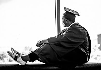 A black college graduate looks out of the window