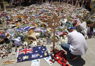 A mourner lights candles as people gather around floral tributes outside Bondi Pavilion in Sydney on 17 December, 2025, to honour victims of the Bondi Beach shooting.
