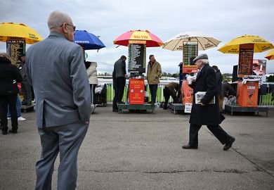 Racegoers walk past bookmakers' betting stands on the final day of the Grand National Festival horse race meeting, illustrating the low success rates for some UK research council grant schemes.