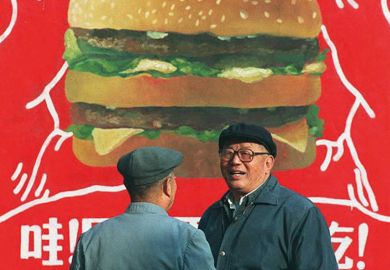 Two Chinese men in front of a billboard advertisement for a burger Two Chinese men in front of a billboard advertisement for a burger