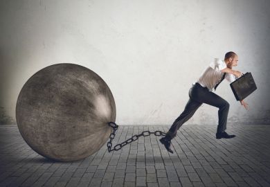 Businessman running with ball and chain on ankle