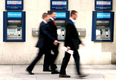 Businessmen walk past cash machines
