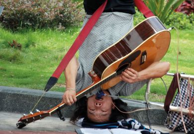 Busker playing guitar upside-down Busker playing guitar upside-down